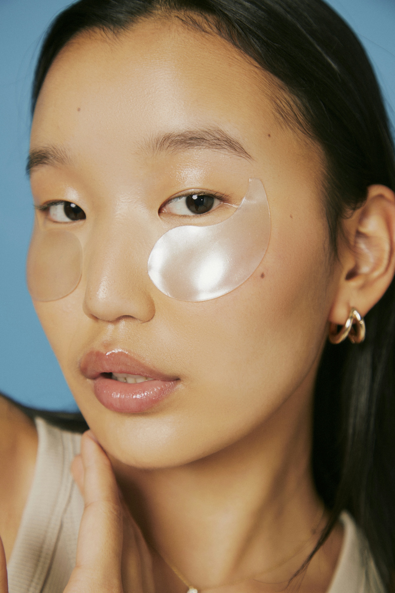 Close-up portrait of a woman with a hydrating eye patch under one eye